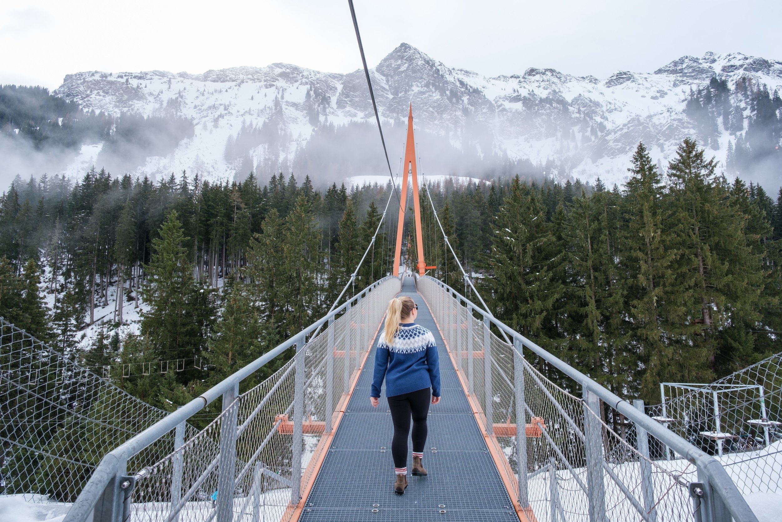 Natasha Walks Across A Bridge In Winter In Austria
