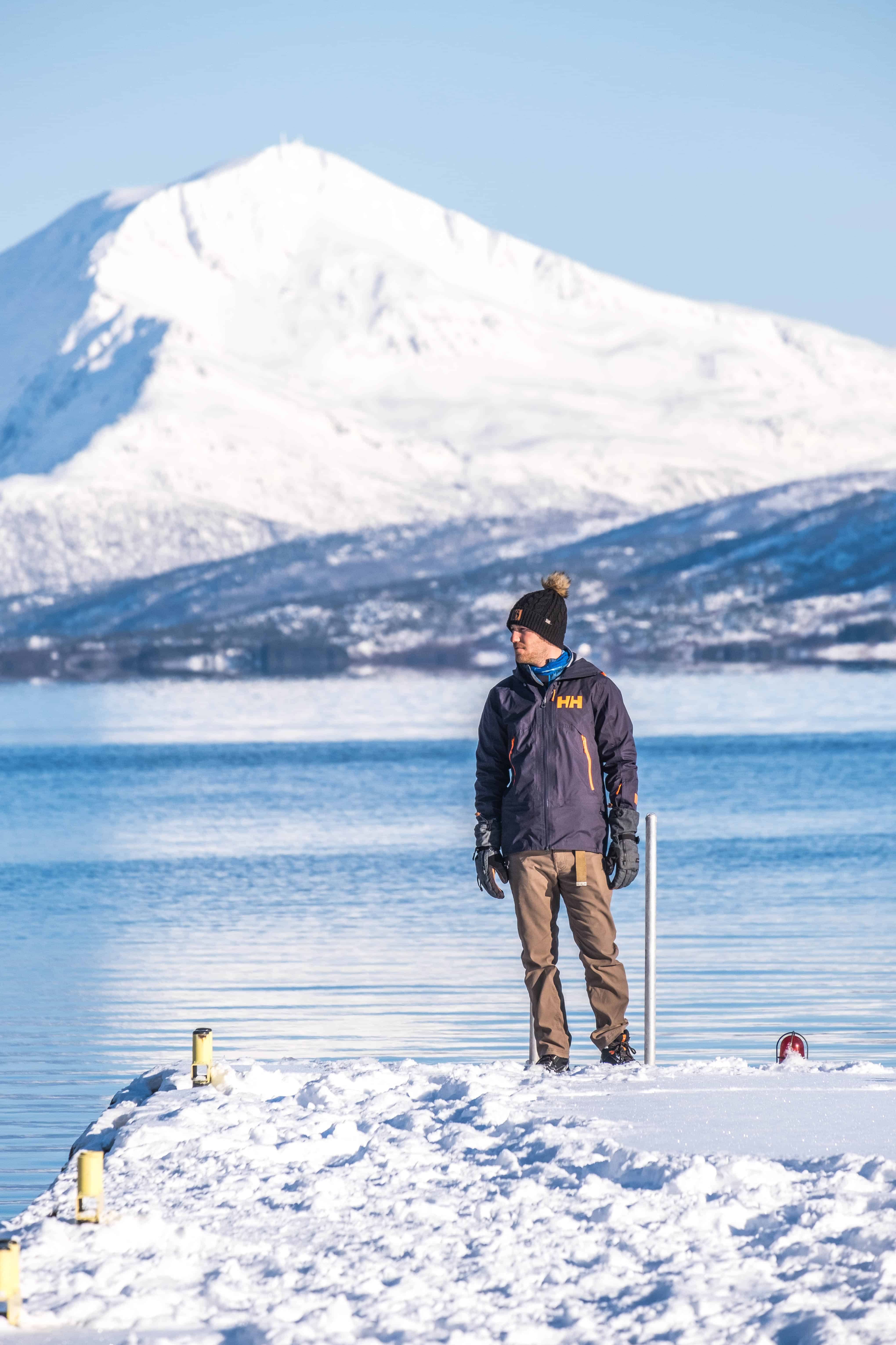 Cameron Stands On End Of Dock In Norway In Winter